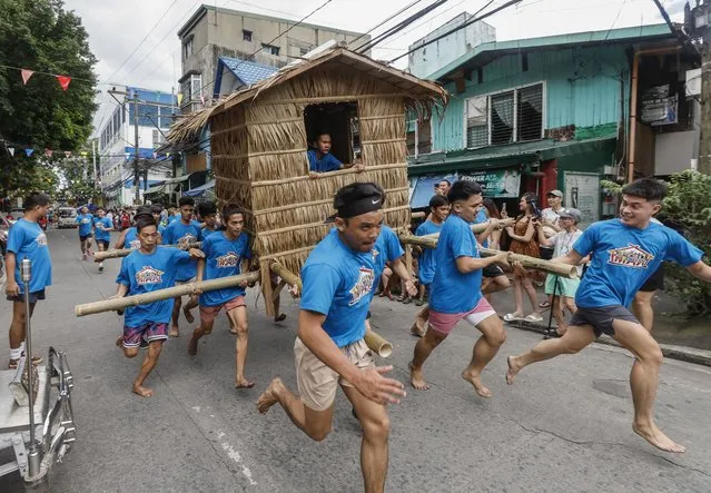 Participants run through a street carrying a palm hut during the annual Buhat Kubo Race (Hut Race) in Ugong Village of Pasig City, Metro Manila, Philippines, 18 November 2023. In celebration of Bayanihan Festival (Festival of Community), Ugong residents held the Hut Race to re-live the Filipino tradition of helping neighbors even in relocating their houses to show a sense of community in the face of adversity. (Photo by Rolex Dela Pena/EPA)