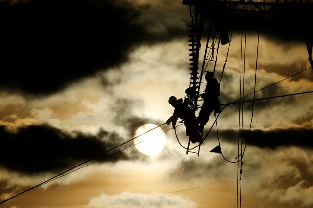 Technicians work on an electricity pylon as part of the maintenance of high-tension electricity power lines during sunset in Roye, France, February 11, 2019. (Photo by Pascal Rossignol/Reuters)