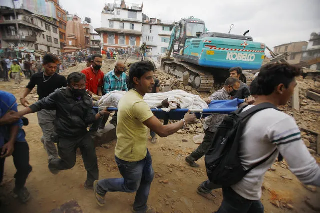 Volunteers carry the body of a victim on a stretcher, recovered from the debris of a building that collapsed after an earthquake  in Kathmandu, Nepal, Saturday, April 25, 2015. (Photo by Niranjan Shrestha/AP Photo)