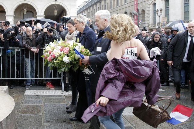 FEMEN activists with Le Pen Top Fascist painted on their bodies appear as France's far-right National Front president Marine Le Pen, center, places a wreath at Joan of Arc Statue during its annual May Day march, in Paris, France, Friday, May 1, 2015. (Photo by Francois Mori/AP Photo)