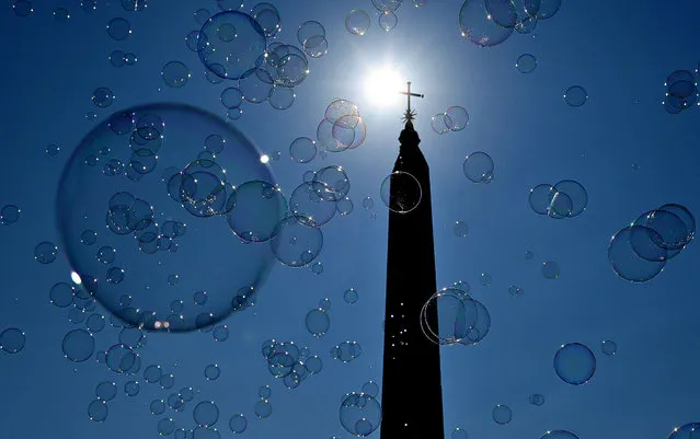 Soap bubbles are silhouetted against the sun and the Egyptian Flaminio obelisk on October 14, 2018 on Piazza del Popolo (People's Square) in central Rome. (Photo by Alberto Pizzoli/AFP Photo)