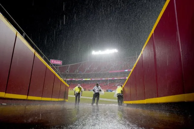 Security guards stand off the field at Arrowhead Stadium as a steady rain falls during halftime of an NFL football game between the Kansas City Chiefs and the Buffalo Bills Sunday, October 10, 2021, in Kansas City, Mo. The start of the second half has been delayed because of lightning in the area. (Photo by Charlie Riedel/AP Photo)