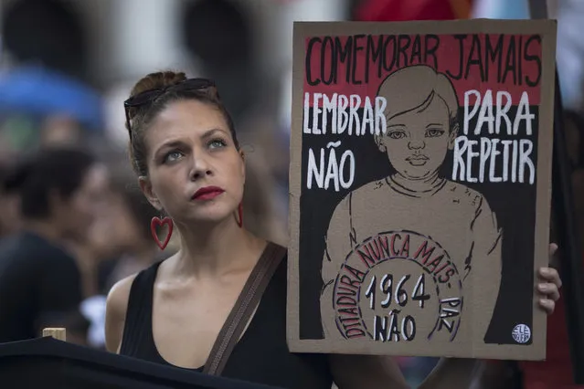A woman holds a sign that reads in Portuguese “Never commemorate, remember to not repeat. Dictatorship never more”, during a protest against the military coup of 1964 in Rio de Janeiro, Brazil, Sunday, March 31, 2019. Brazil's president Jair Bolsonaro, a former army captain who waxes nostalgic for the 1964-1985 dictatorship, asked Brazil's Defense Ministry to organize "due commemorations" on March 31, the day historians say marks the coup that began the dictatorship. (Photo by Leo Correa/AP Photo)