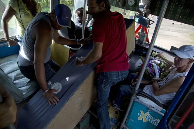 In this February 5, 2014 photo, people carry a mock coffin inside a bus as they head to the local cemetery to celebrate the Burial of Pachencho in Santiago de Las Vegas, Cuba. (Photo by Enric Marti/AP Photo)