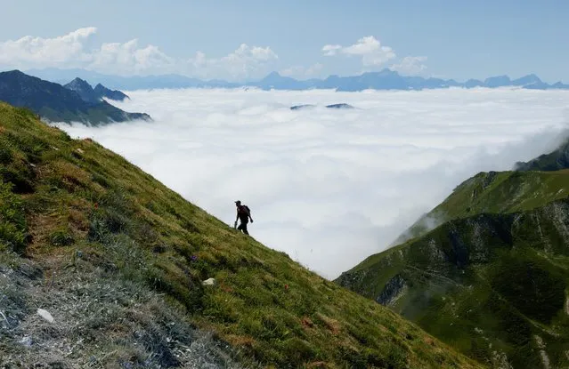 A hiker walks up to the Moleson summit during a cloud inversion in Gruyeres, Switzerland on August 25, 2021. (Photo by Denis Balibouse/Reuters)
