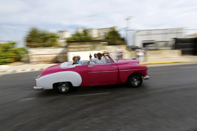 Tourists ride in a vintage car in Havana, March 17, 2016. (Photo by Ivan Alvarado/Reuters)