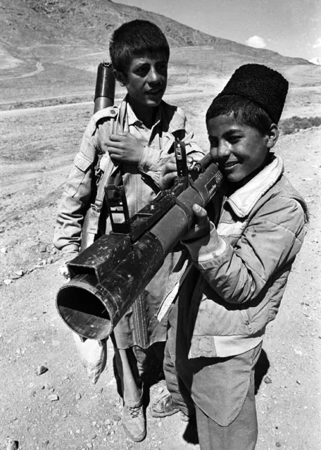 Two Afghan boys play with the empty canisters of a Soviet made anti-tank missile in Kabul, May 1989. (Photo by Richard Ellis/Reuters)