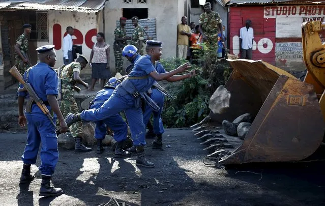 A policeman throws a stone as he clears a barricade which was set up by protesters in Bujumbura, Burundi, May 10, 2015. (Photo by Goran Tomasevic/Reuters)