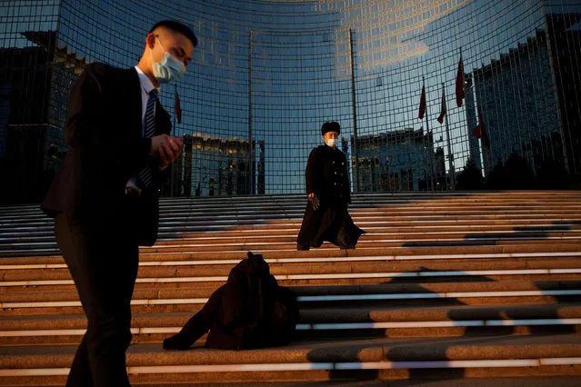People wearing face masks walk on the steps of a luxury hotel in an upscale business and shopping area as the coronavirus disease (COVID-19) outbreak continues in Beijing, China, December 1, 2021. (Photo by Thomas Peter/Reuters)