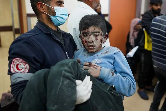A medic carries a wounded Palestinian boy into the Al-Aqsa Martyrs Hospital in Deir al-Balah on March 19, 2024, following Israeli bombardment in the Nuseirat refugee camp in the central Gaza Strip amid ongoing battles between Israel and the militant group Hamas. (Photo by AFP Photo)