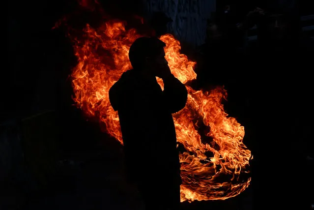 A person stands near a fire during a protest of European farmers over price pressures, taxes and green regulation, on the day of an EU Agriculture Ministers meeting in Brussels, Belgium on February 26, 2024. (Photo by Yves Herman/Reuters)