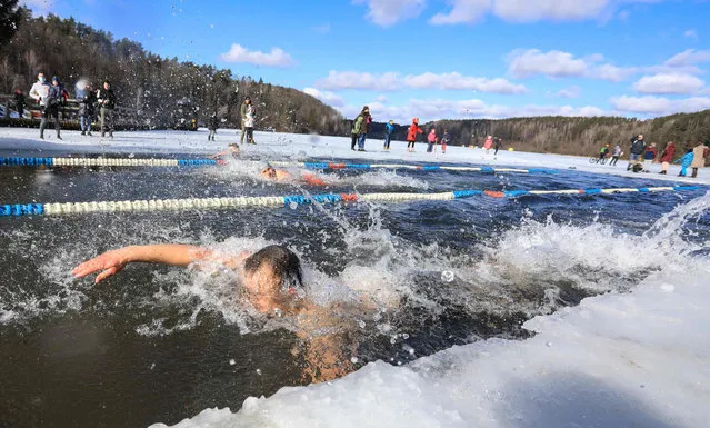 People swim at an annual winter swimming competition in freezing water, temperatures outside dropping to minus 2 degrees Celsius, in Vilnius, Lithuania, on March 2, 2021. (Photo by Petras Malukas/AFP Photo)