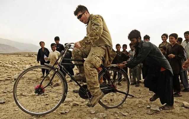 Sgt. Lucas Simmons, team leader attached to Laghman Provincial Reconstruction Team, rides a bike given to him by a local child during a multi-day operation August 21 in Alingar District, Laghman Province. The PRT, combined with assets from the 45th Infantry Brigade, conducted a cordon and search in a village thought to be home to IED makers and Taliban fighters. (Photo by Staff Sgt. Ryan Crane/U.S. Air Force)