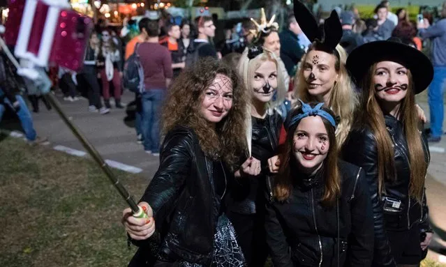 People wearing costumes and face paint pose as they take part in a “Zombie walk” in Tel Aviv as part of the Jewish holiday of Purim on March 11, 2017. The carnival- like Purim holiday is celebrated with parades and costume parties to commemorate the deliverance of the Jewish people from a plot to exterminate them in the ancient Persian empire 2,500 years ago, as described in the Book of Esther. (Photo by Jack Guez/AFP Photo)
