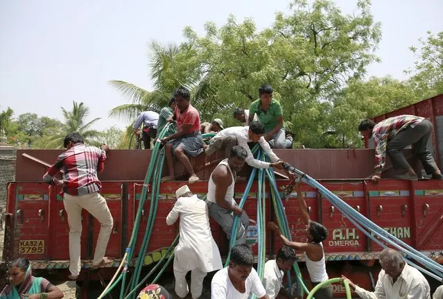 Residents climb a government-run water tanker with plastic hoses in Masurdi village, in Latur, India, April 16, 2016. (Photo by Danish Siddiqui/Reuters)