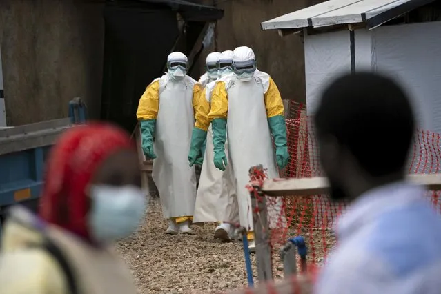In this Tuesday, July 16, 2019 photo, health workers wearing protective gear begin their shift at an Ebola treatment center in Beni, Congo. On July 17, the World Health Organization declared the Ebola outbreak an international emergency after it spread to eastern Congo's biggest city, Goma. (Photo by Jerome Delay/AP Photo)