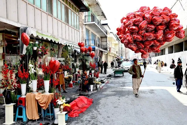A street vendor carries heart shaped balloons as he waits for customers on Valentine's Day in Kabul on February 14, 2022. (Photo by Ahmad Sahel Arman/AFP Photo)