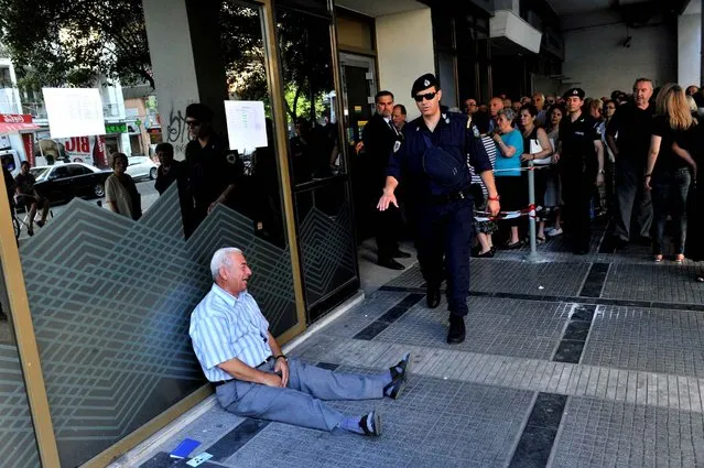 An elderly man is crying outside a national bank branch as pensioners queue to get their pensions, with a limit of 120 euros, in Thessaloniki on 3 July, 2015. Greece is almost evenly split over a crucial weekend referendum that could decide its financial fate, with a “Yes” result possibly ahead by a whisker, the latest survey Friday showed. (Photo by Sakis Mitrolidis/AFP Photo)