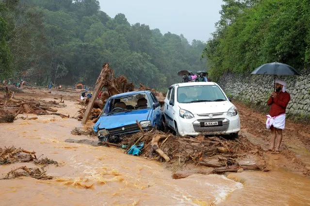 A man stands next to damaged cars after a landslide caused by torrential monsoon rains at Puthumala near Meppadi, Wayanad district, in Kerala, India, August 14, 2019. (Photo by Reuters/Stringer)