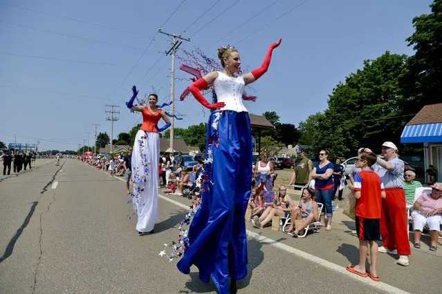 Kaitlyn Grimes, 26, of Erie, Pa., left, and Carrie Bach, 37, of Millcreek Township, Pa., walk on stilts during Millcreek's 50th annual Fourth of July parade in Millcreek Township, Pa., Saturday, July 4, 2015. (Photo by Sarah Crosby/Erie Times-News via AP Photo)