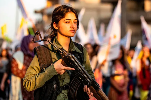 A member of the Kurdish Internal Security Police Force of Asayish stands guard as Syrian Kurdish demonstrate against Turkish threats to invade the Kurdish region, in the northeastern city of Qamishli on August 27, 2019. The Kurdish authorities in northeast Syria said Tuesday their forces had started to withdraw from outposts along the Turkish border after a US-Turkish deal for a buffer zone there. (Photo by Delil Souleiman/AFP Photo)