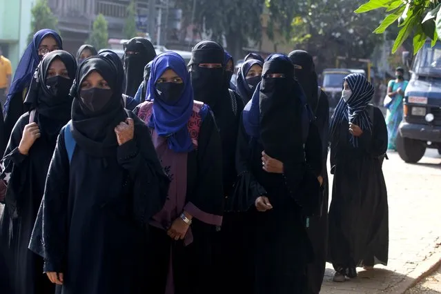 Indian girl students who were barred from entering their classrooms for wearing hijab, a headscarf used by Muslim women, walk outside their college in Udupi, India, Monday, February 7, 2022. Muslim girls wearing hijab are being barred from attending classes at some schools in the southern Indian state of Karnataka, triggering weeks of protests by students. (Photo by AP Photo/Stringer)