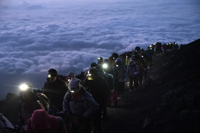 A group of hikers climb to the top of Mount Fuji just before sunrise as clouds hang below the summit Tuesday, August 27, 2019, in Japan. (Photo by Jae C. Hong/AP Photo)