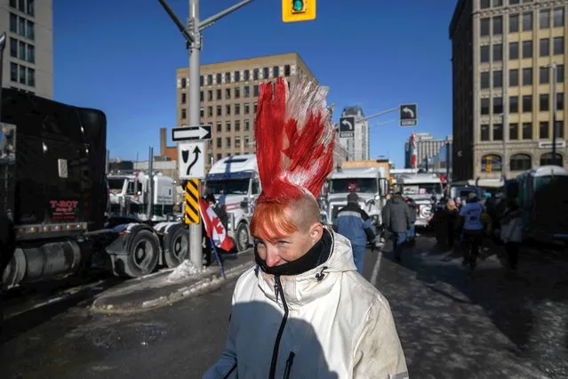 A demonstrator walks between trucks during a protest by truck drivers over Covid-19 pandemic health rules and the Trudeau government, outside the parliament of Canada in Ottawa, Ontario, on February 13, 2022. (Photo by Ed Jones/AFP Photo)