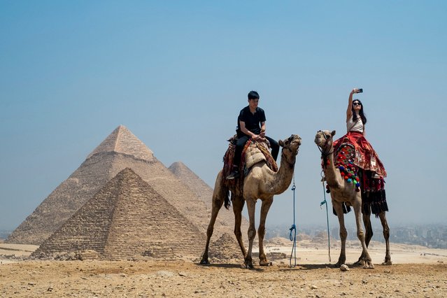 A tourist takes a selfie while riding a camel at the Giza Pyramids Necropolis on the outskirts of Giza on April 30, 2024. (Photo by Jewel Samad/AFP Photo)