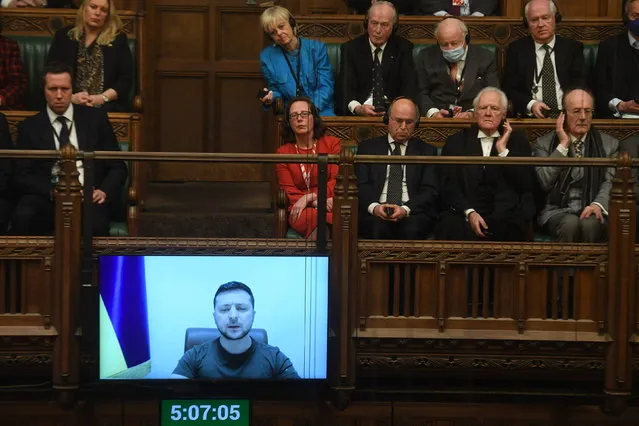 In this photo provided by UK Parliament, Ukrainian President Volodymyr Zelenskyy is displayed on the screen as he addresses British lawmakers in the House of Commons in London, Thursday March 8, 2022. Speaking by video link, the Ukrainian leader urged the U.K. to increase sanctions on Russia, to recognize Russia as “a terrorist country” and to keep Ukraine’s skies safe. He was given a standing ovation by members from all parties in the House of Commons. (Photo by Jessica Taylor/UK Parliament via AP Photo)