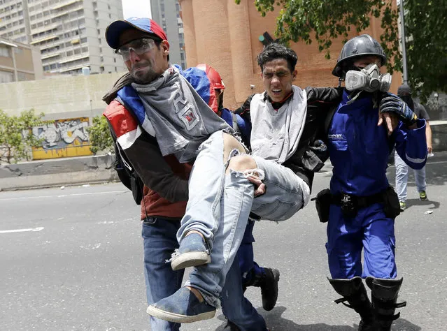 A protester is carried after being injured in clashes with security forces during anti-government protests in Caracas, Venezuela, Wednesday, April 19, 2017. (Photo by Ariana Cubillos/AP Photo)