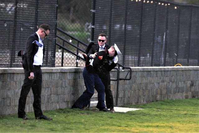 A U.S. Secret Service agent helps a marine stay steady as the Marine One carrying U.S. President Joe Biden lands, kicking up dust and causing a powerful wind, at the Del Mar landing zone in Del Mar, California, U.S. March 13, 2023. (Photo by Leah Millis/Reuters)