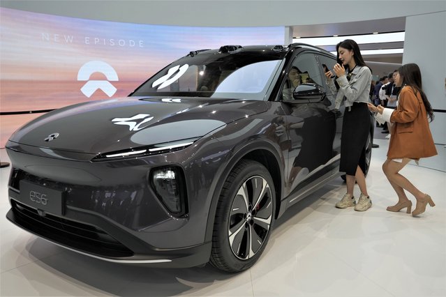 Attendees look at the es6, the latest electric vehicle from Chinese automaker NIO during the Auto Shanghai 2023 show in Shanghai, Tuesday, April 18, 2023. (Photo by Ng Han Guan/AP Photo)