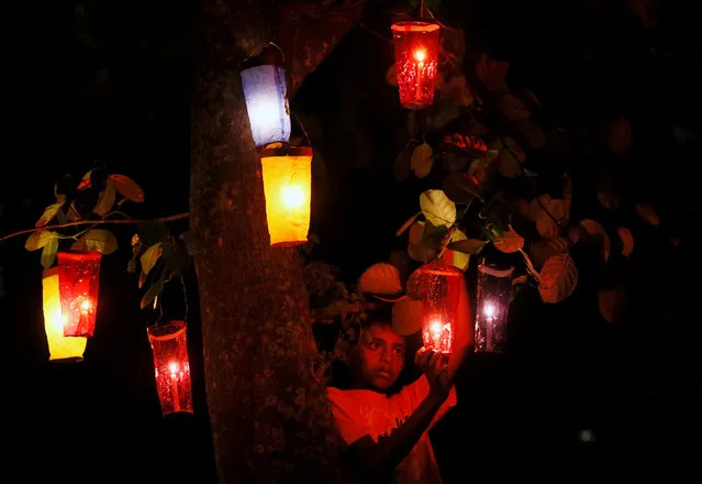 A boy hangs Vesak buckets on a tree, at a house, during the birth anniversary of Buddha, also known as Vesak Day, in Colombo, Sri Lanka May 10, 2017. (Photo by Dinuka Liyanawatte/Reuters)