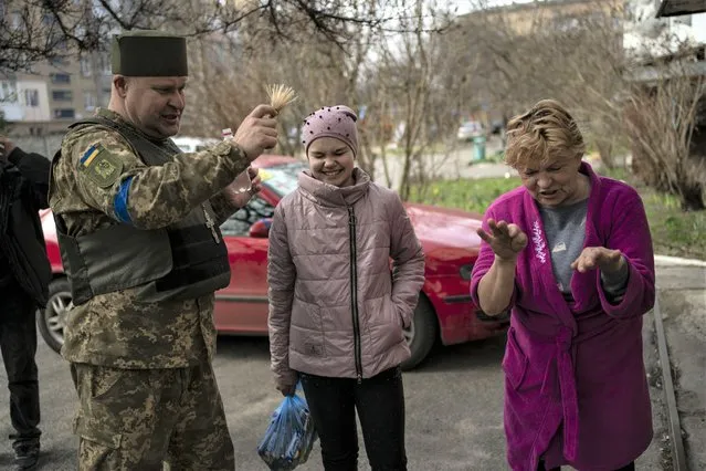 Chaplain Dmitri blesses a group of neighbors in Bucha, in the outskirts of Kyiv, Ukraine, Friday, April 8, 2022. (Photo by Rodrigo Abd/AP Photo)