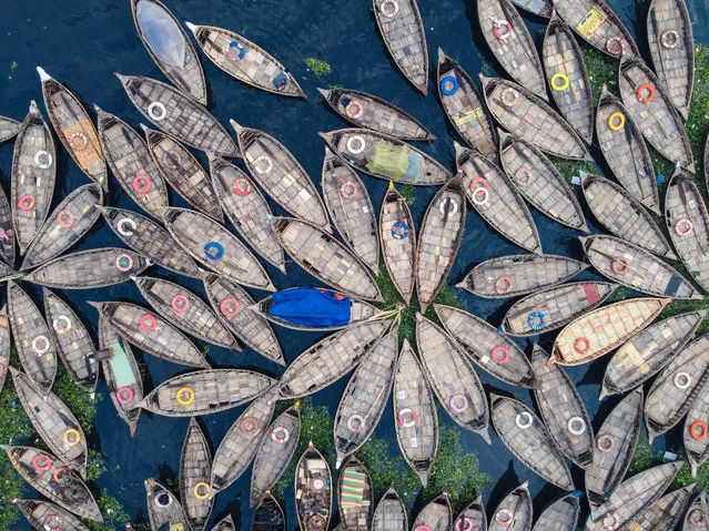 Hundreds of wooden boats resemble like flowers in Dhaka River Port, Bangladesh as they fan out around their moorings on March 29, 2022. The boats, decorated with colourful patterned rugs, are ready to transport workers from the outskirts of the city to their jobs in the centre. The Buriganga river is used as a route into Dhaka city for millions of workers every day. The Bangladeshi capital is one of the most densely populated in the world and home to around 19 million people. (Photo by Mustasinur Rahman Alvi/ZUMA Press Wire/Rex Features/Shutterstock)
