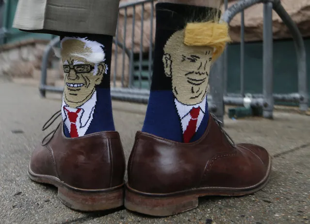 Colorado Gov. John Hickenlooper shows off his socks--one with Democratic presidential candidate Bernie Sanders and the other with Republican candidate Donald Trump – before entering his former brewpub for a book signing event to mark the release of his autobiography Thursday, May 26, 2016, in Denver. Hickenlooper, who is term-limited, is doing book talk rounds this week, reviving speculation that he is positioning himself to join Hillary Clinton's presidential campaign ticket. (Photo by David Zalubowski/AP Photo)