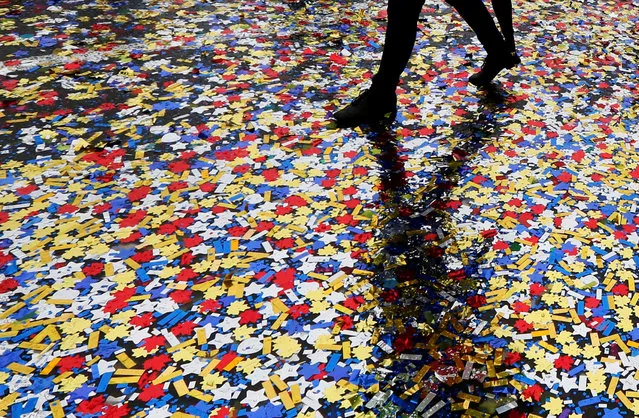 A woman walks through confetti covering a street during an annual carnival to celebrate International Children's Day in central Krasnoyarsk, Siberia, Russia, June 1, 2016. (Photo by Ilya Naymushin/Reuters)