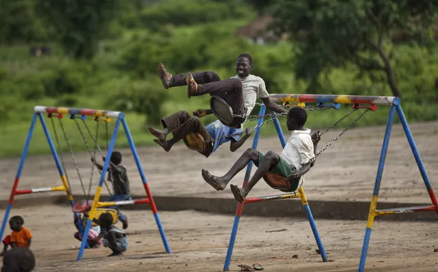 South Sudanese refugee children play on swings during morning break in the yard of the Ombechi nursery school, which has over 500 pupils and is supported by UNICEF and Save the Children, in Bidi Bidi, Uganda Wednesday, June 7, 2017. Bidi Bidi is a sprawling complex of mud-brick houses that is now the world's largest refugee settlement holding some of those who fled the civil war in South Sudan, which has killed tens of thousands and driven out more than 1.5 million people in the past three years, creating the world's largest refugee crisis. (Photo by Ben Curtis/AP Photo)