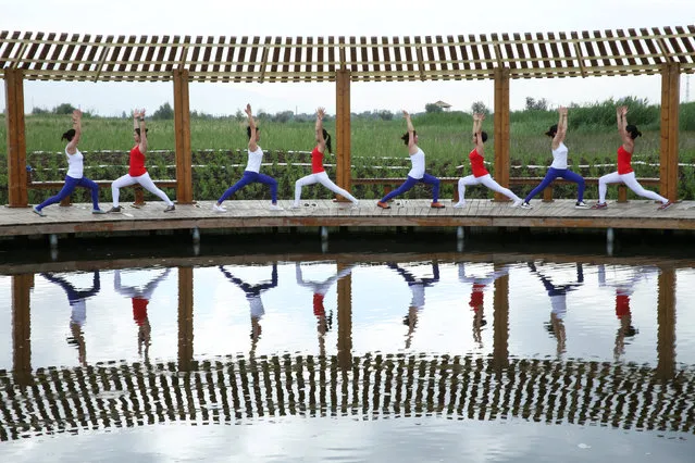 Yoga enthusiasts practice yoga at a wetland park on International Yoga Day, in Zhangye, China June 21, 2017. (Photo by Reuters/Stringer)