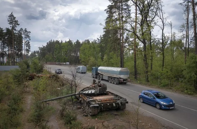 Cars pass by Russian tanks destroyed in a recent battle against Ukrainians in the village of Dmytrivka, close to Kyiv, Ukraine, Monday, May 23, 2022. (Photo by Efrem Lukatsky/AP Photo)