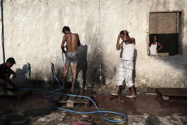 Migrants wash themselves outside an abandoned hotel where dozens of migrants have been living the last weeks at Kos town, on the southeastern island of Kos, Monday, August 10, 2015. (Photo by Yorgos Karahalis/AP Photo)