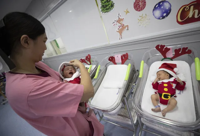 A nurse holds newborn babies dressed in Santa costumes on Christmas eve at the Synphaet hospital in Bangkok, Thailand, Tuesday, December 24, 2019. (Photo by Sakchai Lalit/AP Photo)