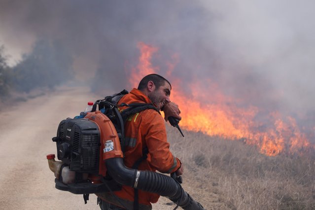 A man reacts as he attempts to extinguish flames following a rocket attack from Lebanon, amid cross-border hostilities between Hezbollah and Israel, in the Israeli-occupied Golan Heights on September 20, 2024. (Photo by Jim Urquhart/Reuters)