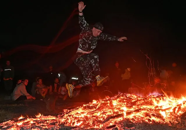 A man jumps over a fire during the celebration of the summer solstice at a festival in the village of Okunevo in Omsk region, Russia on June 21, 2022. (Photo by Alexey Malgavko/Reuters)