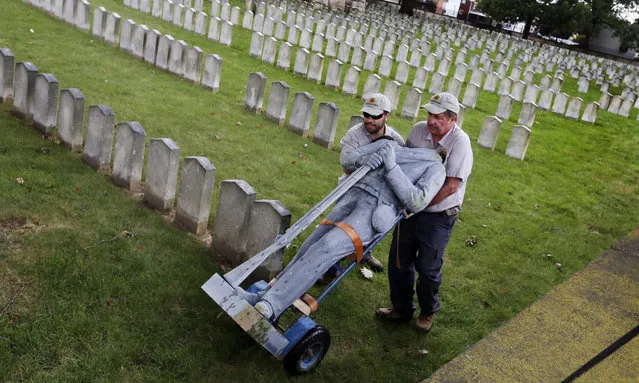 Bert Cambron, left, and Mark Wilson employees of Dayton National Cemetery move the vandalized Confederate soldier statue that stood in Camp Chase Confederate Cemetery on Tuesday, August 22, 2017, in Columbus, Ohio. Columbus police say vandals appear to have climbed on an arched memorial at Camp Chase Confederate Cemetery and toppled the statue atop the monument to the ground. The soldier's head and hat were knocked off. Police say the vandals took the head but left the hat. (Photo by Eric Albrecht/The Columbus Dispatch via AP Photo)