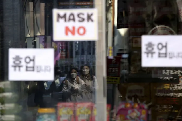 Women wearing a face mask are reflected on a window of a temporarily closed store in Seoul, South Korea, Wednesday, March 18, 2020. The sign reads: “Temporarily closed store”. (Photo by Ahn Young-joon/AP Photo)
