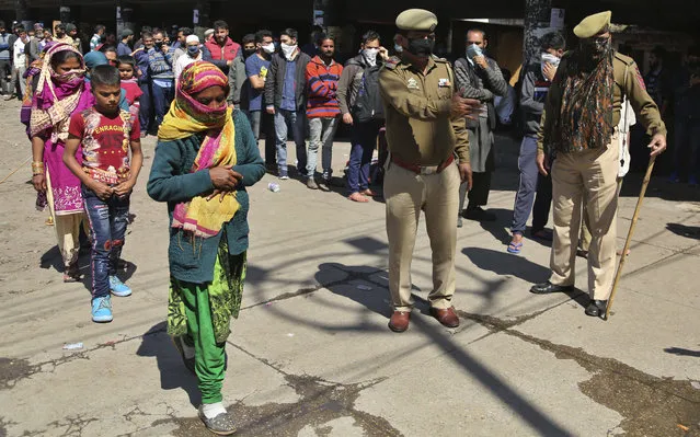 Indian passengers who got stranded at a bus terminal line up for free food being distributed by shop keepers during a day long lockdown amid growing concerns of coronavirus in Jammu, India, Sunday, March 22, 2020. India is observing a 14-hour “people's curfew” called by Prime Minister Narendra Modi in order to stem the rising coronavirus caseload in the country of 1.3 billion. (Photo by Channi Anand/AP Photo)