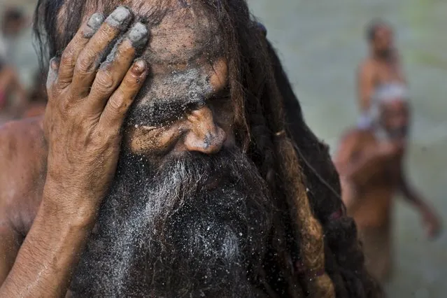 An Indian Sadhu, or Hindu holy man, rubs ash on his face after a bath in the Godavari River during Kumbh Mela, or Pitcher Festival, in Nasik, India, Saturday, August 29, 2015. (Photo by Bernat Armangue/AP Photo)