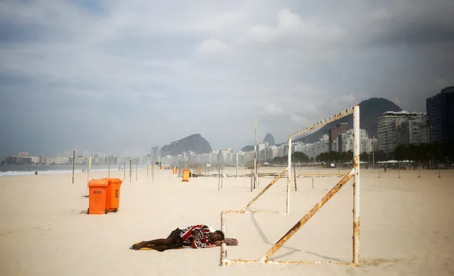 A man sleeps on a goalpost in the morning on Leme beach in Rio de Janeiro, Brazil, May 5, 2016. (Photo by Nacho Doce/Reuters)